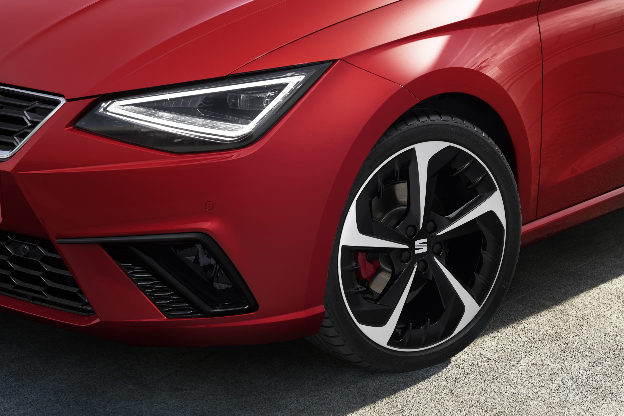 Czerwony SEAT Ibiza zbliżenie na przednie koło i reflektor od strony kierowcy